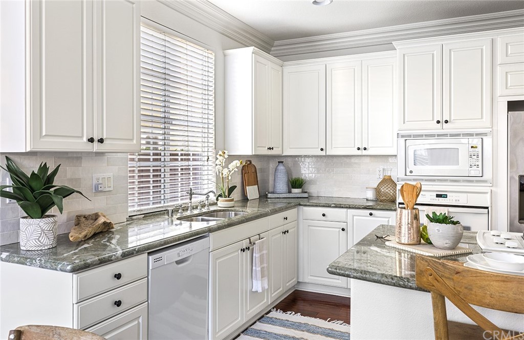 22 Alcott Street Ladera Ranch, CA 92694 - Photo 16 of 46 a kitchen with granite countertop a sink white cabinets and white appliances