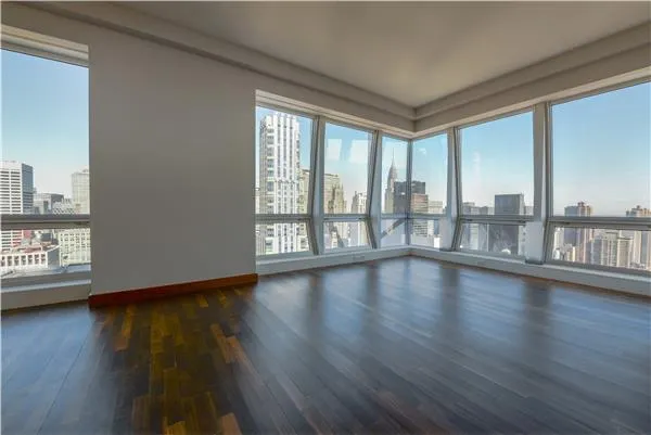 a view of empty room with wooden floor and floor to ceiling window