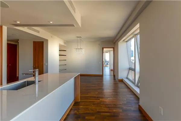 a hallway with wooden floor chandelier and windows