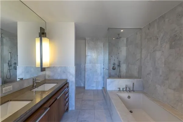 a bathroom with a tub a sink and a large mirror