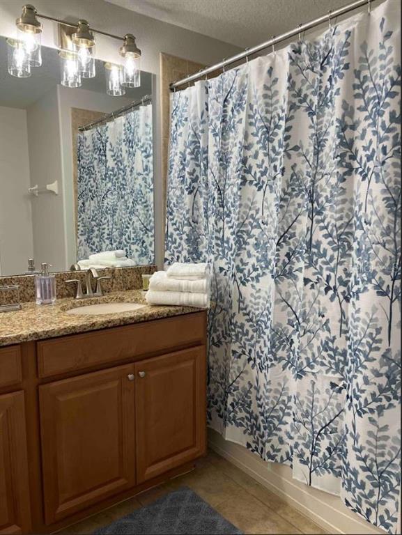 8947 Candy Palm Road Kissimmee, FL 34747 - Photo 16 of 16 a bathroom with a granite countertop sink a mirror and a shower curtain