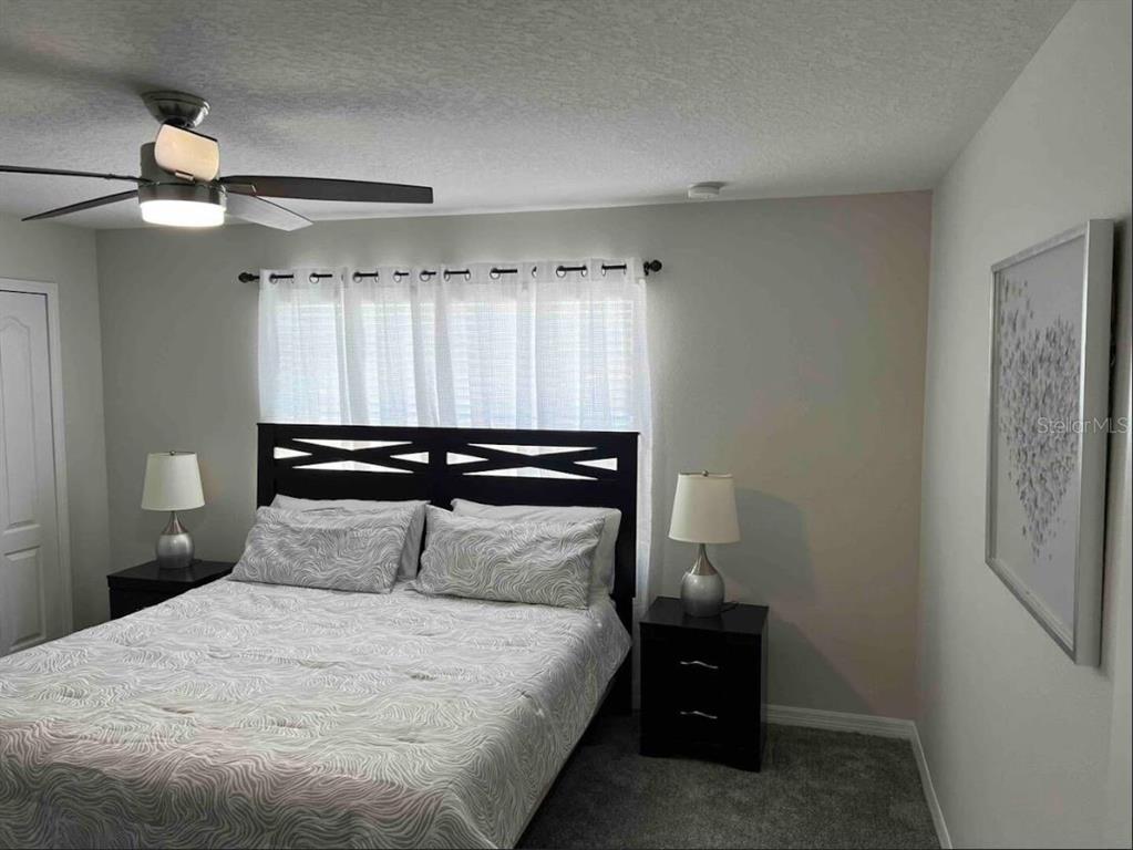 8947 Candy Palm Road Kissimmee, FL 34747 - Photo 10 of 16 a bedroom with a bed and a chandelier