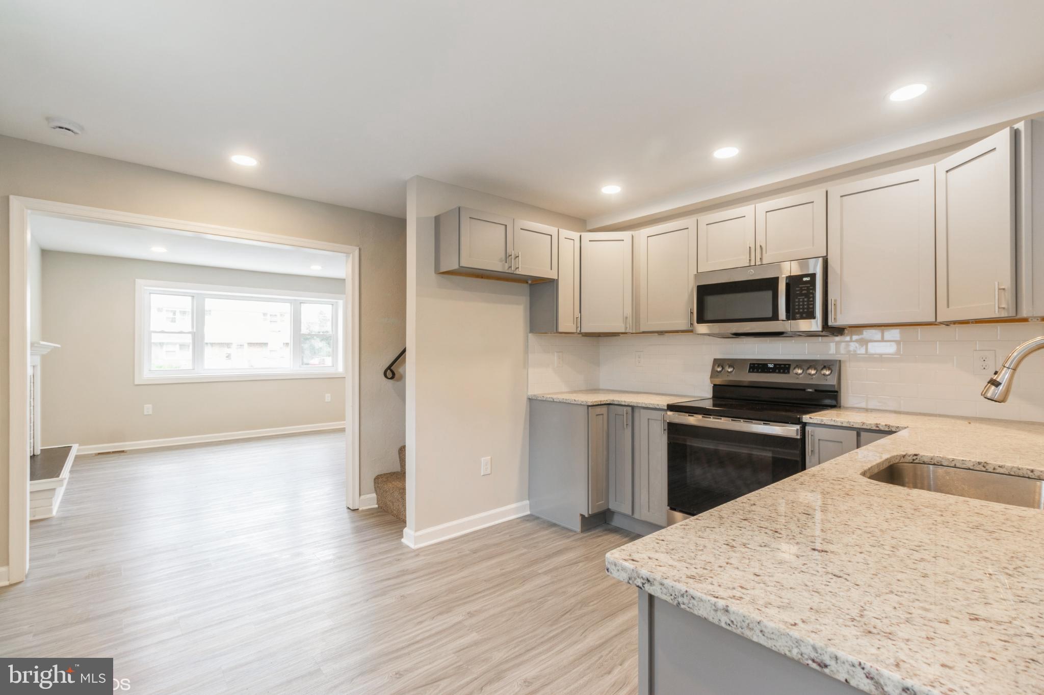 425 Grape Street Warminster, PA 18974 - Photo 8 of 26 a kitchen with granite countertop white cabinets appliances and wooden floor