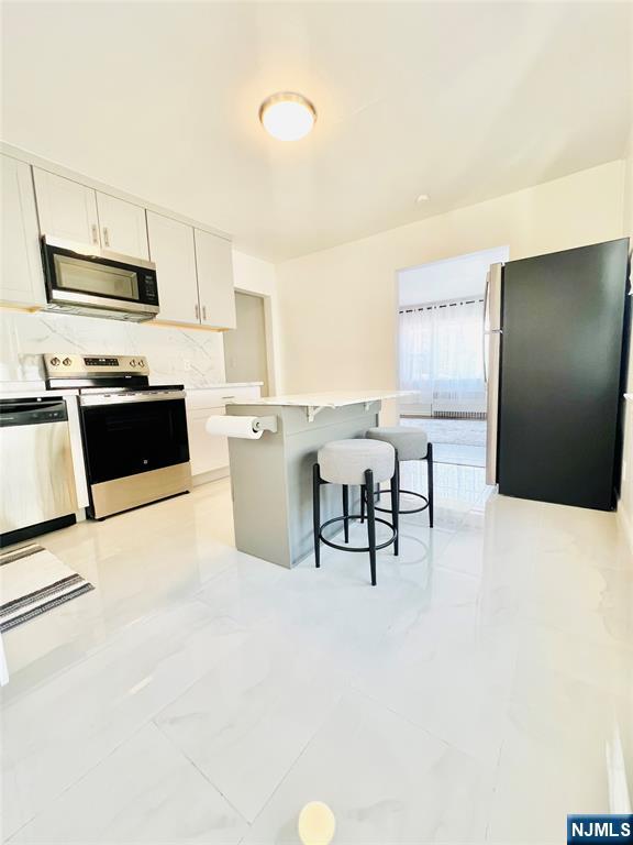18 Pershing Street Garfield, NJ 07026 - Photo 8 of 16 a kitchen with stainless steel appliances a refrigerator a stove a sink a dining table and chairs