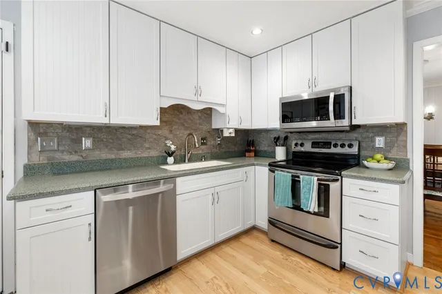 a kitchen with granite countertop white cabinets stainless steel appliances and a sink