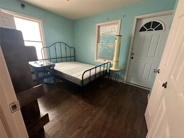 a bedroom with a bed next to a window with wooden floor