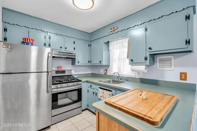 a kitchen with stainless steel appliances granite countertop a refrigerator sink stove and white cabinets