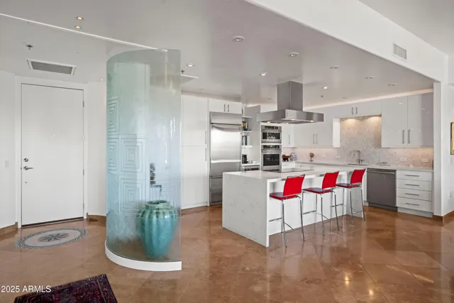 a kitchen with stainless steel appliances kitchen island granite countertop a dining table chairs stove and sink