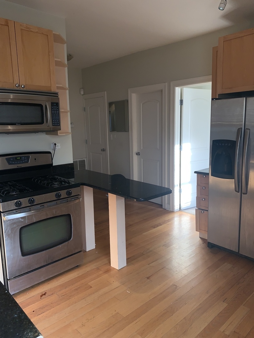 839 East 52nd Street, Unit 3 Chicago, IL 60615 - Photo 3 of 18 a kitchen with stainless steel appliances granite countertop a stove a microwave and a refrigerator