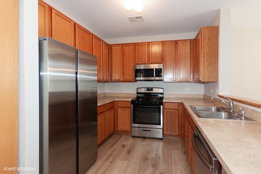 5111 Freeport Court Plainfield, IL 60586 - Photo 7 of 24 a kitchen with stainless steel appliances granite countertop a refrigerator stove microwave and sink