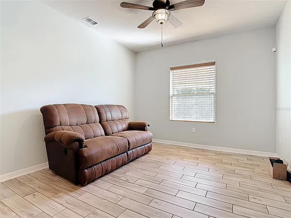 a living room with couches and a ceiling fan