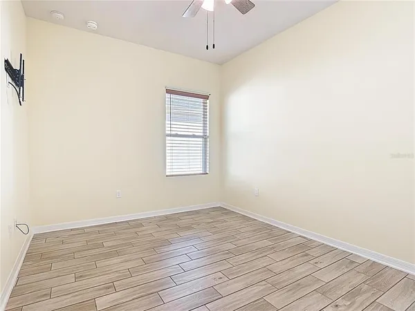 a view of an empty room with wooden floor and a window