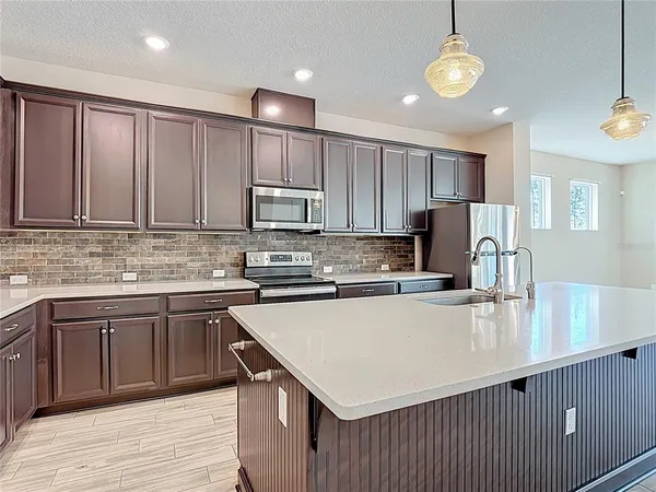 a kitchen with kitchen island granite countertop wooden cabinets a stove top oven a sink and dishwasher