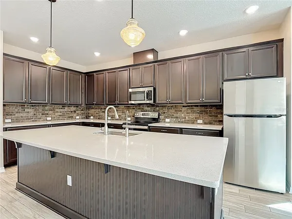 a large kitchen with stainless steel appliances wooden cabinets a refrigerator and a stove