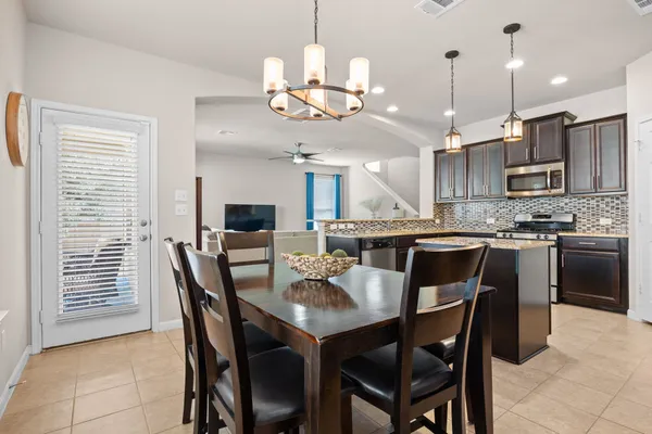 a kitchen with stainless steel appliances kitchen island granite countertop a dining table chairs and a refrigerator