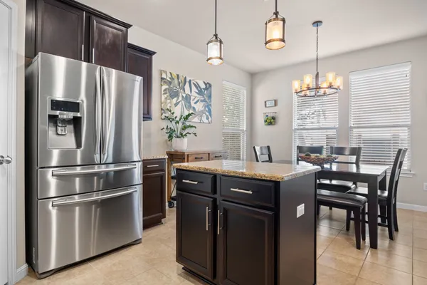 a kitchen with stainless steel appliances granite countertop a refrigerator a stove a sink and a dining table