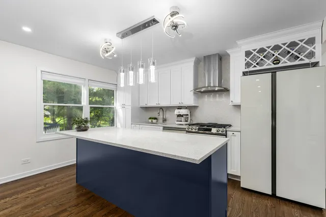 a kitchen with stainless steel appliances granite countertop a sink a stove a refrigerator a center island and wooden floor