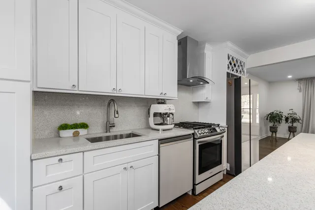 a kitchen with stainless steel appliances granite countertop white cabinets and a stove
