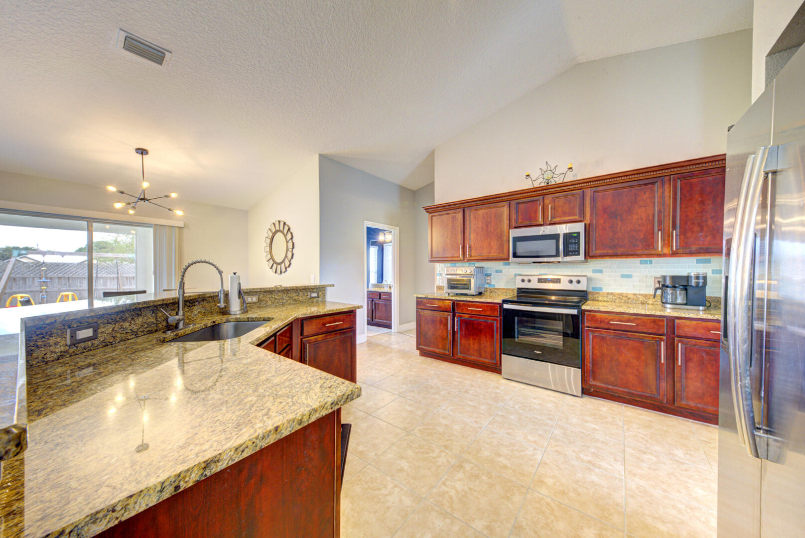 1029 Southwest Bay State Road Port St. Lucie, FL 34953 - Photo 23 of 39 a kitchen with stainless steel appliances granite countertop a sink a stove and a refrigerator