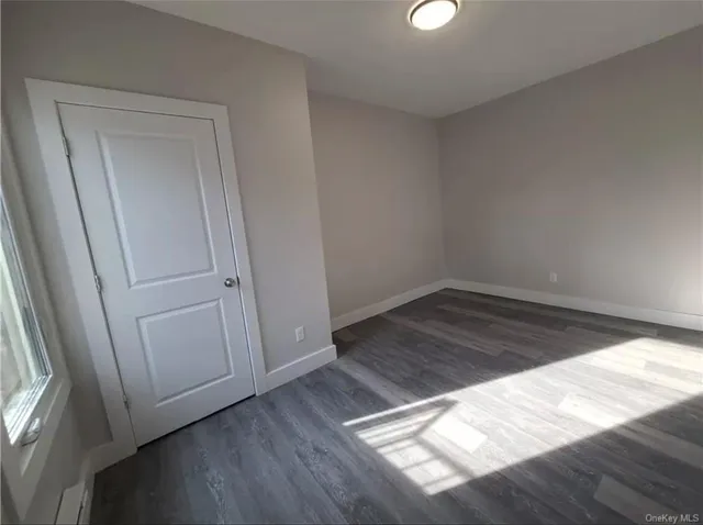an empty room with wooden floor cabinet and door