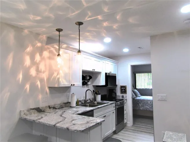 a kitchen with kitchen island granite countertop a sink appliances and cabinets