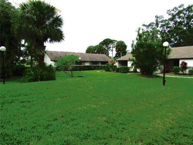 a view of a house with a big yard and a large trees