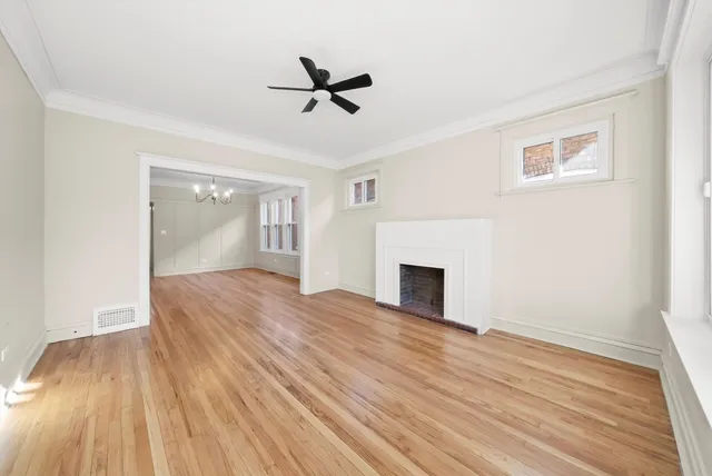 a view of empty room with wooden floor and fan