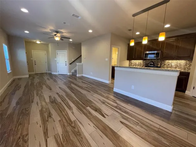 a large kitchen with kitchen island a stove a sink dishwasher and a dining table with wooden floor