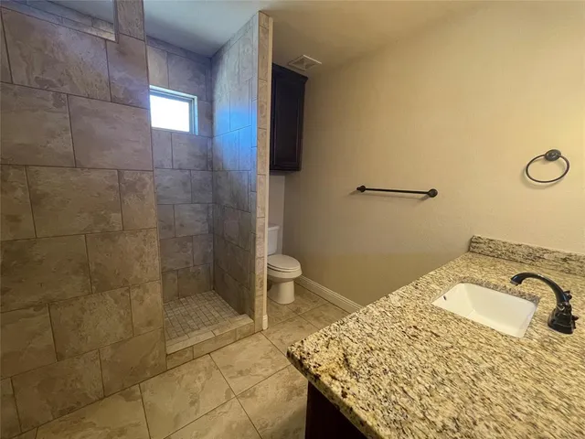 a bathroom with a granite countertop sink toilet and shower