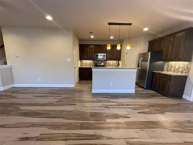 a view of kitchen with refrigerator stove and wooden cabinet