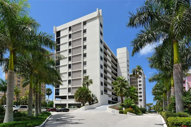 a front view of multi story residential apartment building with yard and parking space