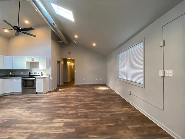 a view of an empty room and a kitchen