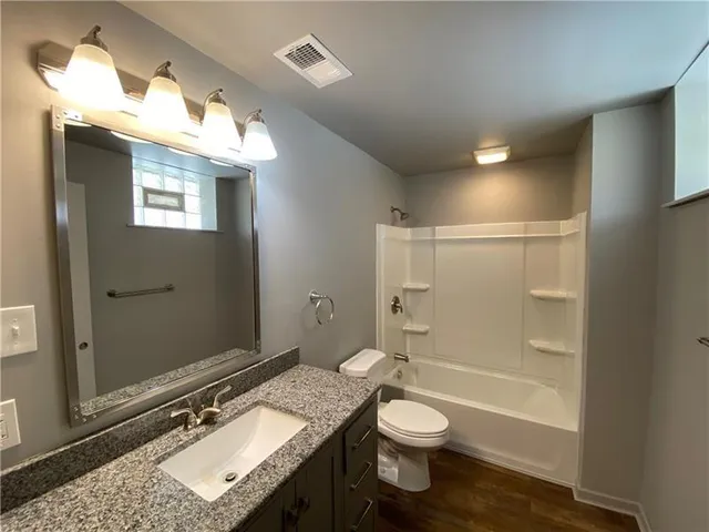 a bathroom with a granite countertop sink toilet a shower and a mirror
