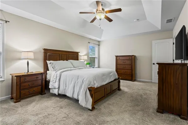 a spacious bedroom with a bed a dresser and a chandelier