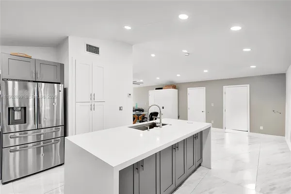 a kitchen with stainless steel appliances a sink a refrigerator and a refrigerator