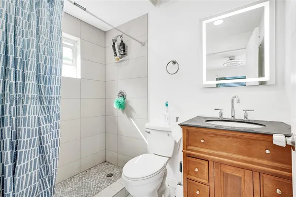 a bathroom with a granite countertop toilet sink and mirror