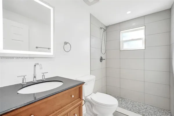 a bathroom with a granite countertop sink toilet and a mirror