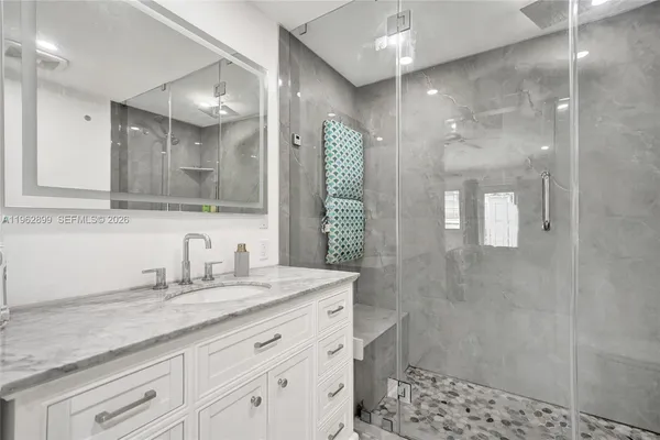 a bathroom with a sink shower and a mirror