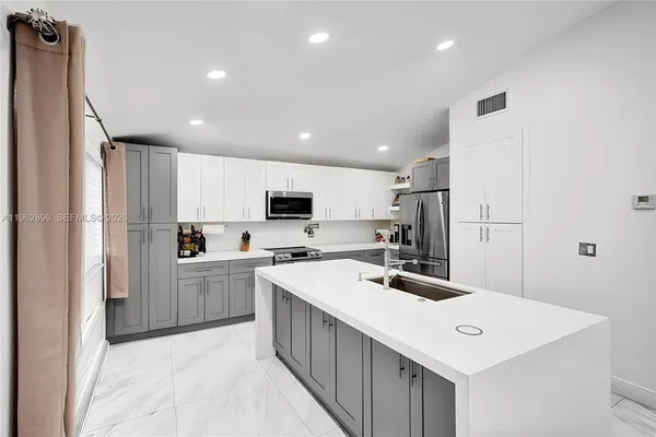 a kitchen that has a lot of cabinets in it and stainless steel appliances