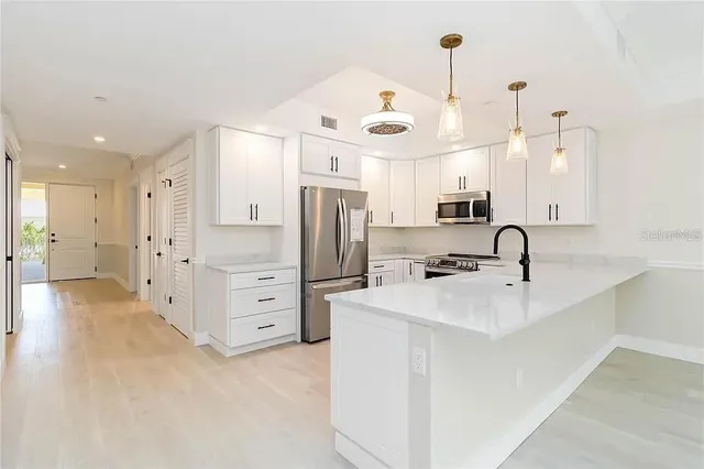 a kitchen with stainless steel appliances a refrigerator sink and white cabinets