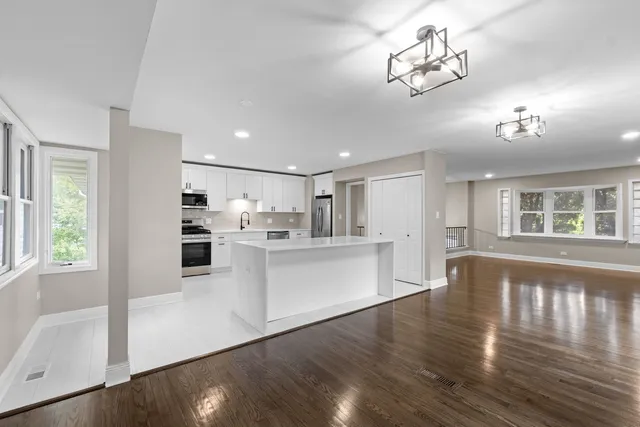 a large white kitchen with lots of counter top space and stainless steel appliances
