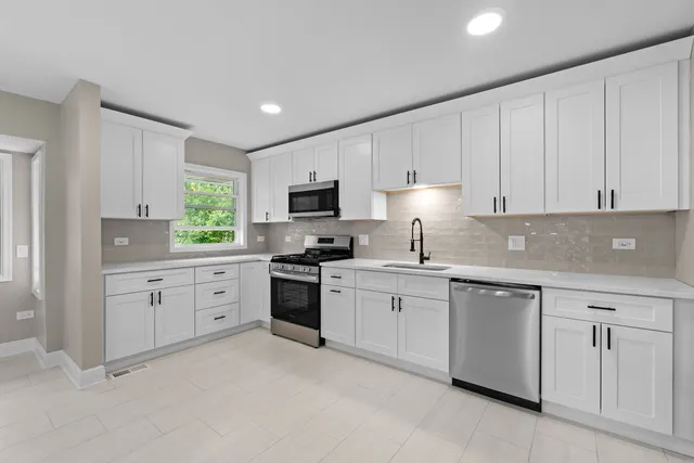 a kitchen with cabinets appliances a sink and a window