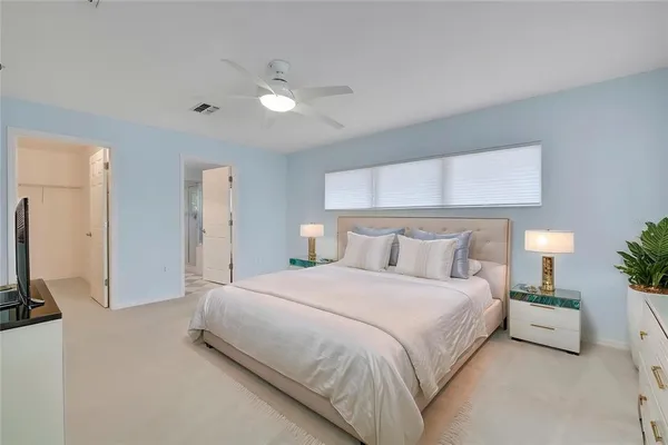 an empty room with chandelier fan and windows