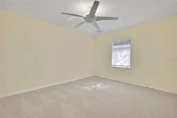 an empty room with a ceiling fan and a window
