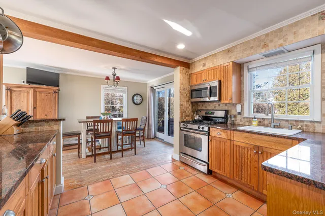 a kitchen with stainless steel appliances granite countertop a stove top oven a sink dishwasher a dining table and chairs with wooden floor