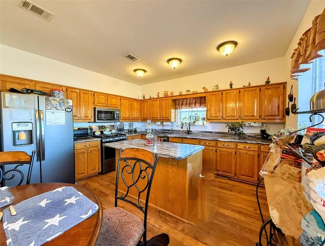a kitchen with stainless steel appliances kitchen island granite countertop a refrigerator and stove