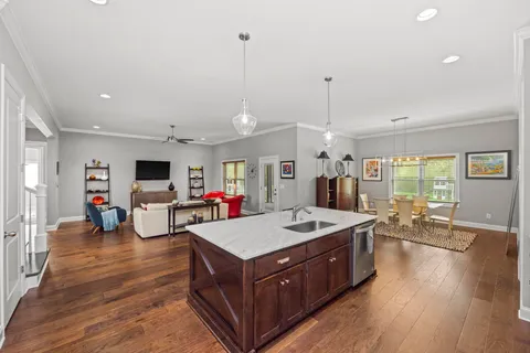 a living room with stainless steel appliances granite countertop furniture wooden floor and a view of kitchen