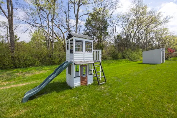 a view of a house with a yard deck and a slide