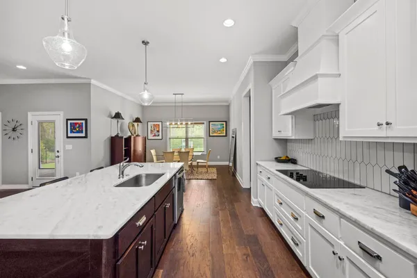 a kitchen with granite countertop a stove a sink a refrigerator and living room view