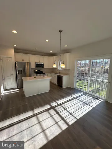 a open kitchen with stainless steel appliances granite countertop a refrigerator a sink dishwasher a stove and a microwave oven with wooden floor